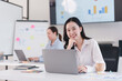 © kenchiro168 - confident businesswoman working on laptop in modern office with charts and notes in background