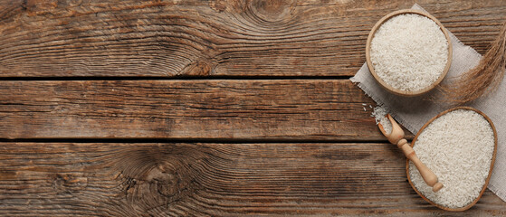 Wall Mural - Bowl and plate with raw rice on wooden background