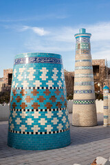 miniatures of traditional Uzbek minarets, adorned with intricate blue and white mosaic pattern, Khiva historic architecture style, Itchan Kala two towers