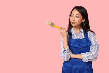Wall Mural - female asian thoughtful painter with brush on pink background