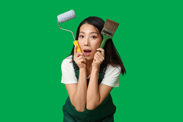 Wall Mural - female asian shocked painter with roller and brush on green background