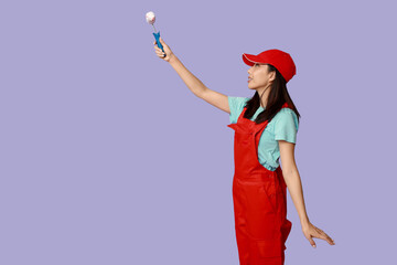 Wall Mural - female asian painter with roller on purple background