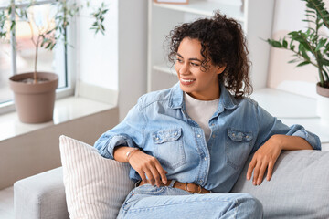 Wall Mural - Young African-American woman resting on sofa at home