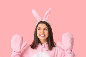 Wall Mural - Happy young woman in bunny costume on pink background. Easter celebration