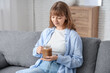 © Pixel-Shot - Young woman with jar mug of tasty iced latte sitting on sofa at home