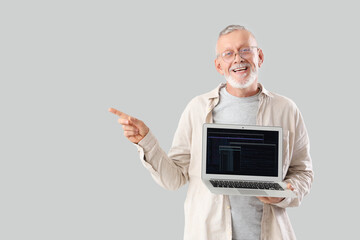 Wall Mural - mature programmer with laptop pointing at something on light background