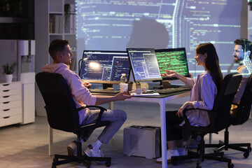 Wall Mural - team of young programmers working in office at night