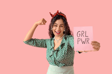 young african-american pin-up woman with grl pwr sign showing muscles on pink background. women's hi
