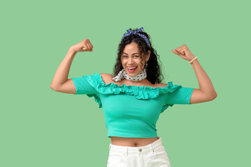 Young African-American pin-up woman showing muscles on green background. Women's History Month