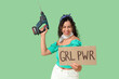 © Pixel-Shot - Young African-American pin-up woman with GRL PWR sign and electric drill on green background. Women's History Month