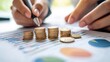 © felix_brönnimann - Hands stacking coins and analyzing financial data on paper with charts, graphs, and reports, representing investment growth and monetary performance strategy.