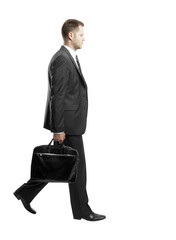 Poster - Side view of a businessman walking in formal attire, holding a briefcase. Minimalist composition on a white isolated background. Business concept