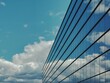 © Anatolii V. - Modern glass building reflecting a bright blue sky with scattered white clouds. The sleek design and geometric perspective create a striking contrast between architecture and nature.