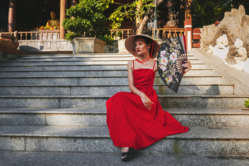 Wall Mural - beautiful young woman tourist with fan in Non La hat in Pagoda in in Vietnam in Asia