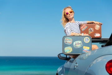 Wall Mural - Happy young woman with retro suitcase travel by car by the sea