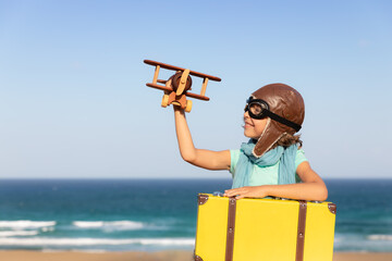 Wall Mural - Happy child playing with toy airplane against blue sea and sky background