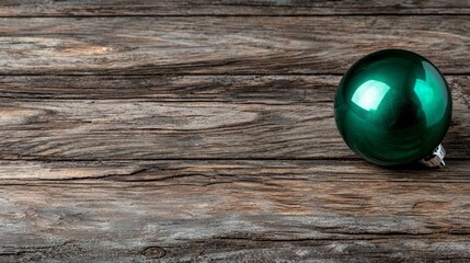 Wall Mural -  a green Christmas ornament sitting atop a wooden table The ornament is round in shape and has a glossy finish, reflecting the light and giving it a festive look