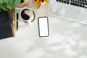 Wall Mural - Overhead view of blank smartphone, coffee, stationery and a laptop, for digital and productivity themes.