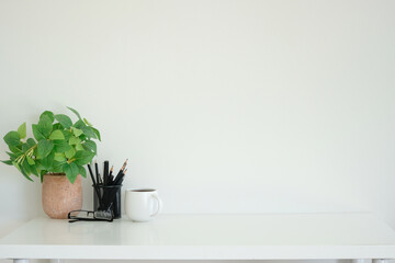 Wall Mural - Office space showcasing a natural plant in a terracotta pot, writing tools in a sleek black holder, and a coffee cup. The minimalist design emphasizes focus and simplicity.