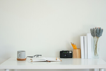 Wall Mural - Modern white desk setup featuring a gray coffee mug, an open notebook with glasses, and a pencil.