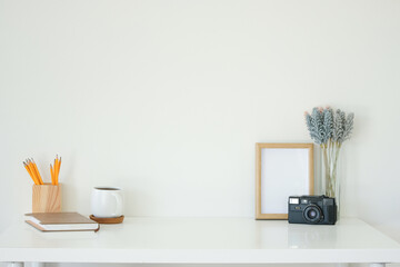 Wall Mural - Creative workspace with glasses, coffee cup, notebook and empty wooden photo frame on white desk.