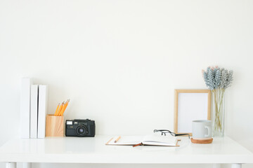 Wall Mural - Creative workspace with glasses, coffee cup, notebook and photo frame on white desk.