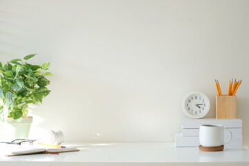 Wall Mural - Bright and airy desk setup with a potted plant, clock, wooden pencil holder and stacked books.