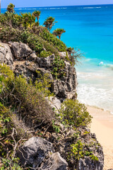 Sticker - A rocky cliff overlooks a beach with a blue ocean