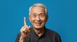 © IbragimovN - Smiling elderly man with raised index finger against blue background