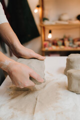 Fototapete - Hands of a female potter making ceramic clay product on the table in the pottery workshop. Potter is sculpting wet clay for ceramics products.