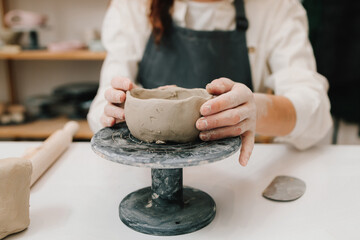 Poster - Female potter hands shows ceramic bowl ready for firing in a kiln. The process of creating ceramic products.