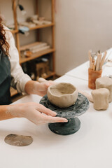 Poster - Female potter hands shows ceramic bowl ready for firing in a kiln. The process of creating ceramic products.