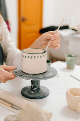 Fototapete - Artist is decorating and painting handmade ceramic clay cup in the creative workshop. Painter is drawing and adding unique designs to the earthenware.