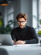 © SOANDLI - Focused businessman working on laptop – Stylish man in black turtleneck and glasses, typing on a laptop in a modern office.