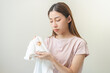 © KMPZZZ - Housewife, asian young maid woman hand in holding white T-shirt, looking at cloth stain, spot dirty or smudge on clothes, dirt stains for cleaning before washing, making household working at home.