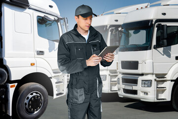 Poster - Fleet manager with digital tablet on a background of trucks