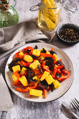 Wall Mural - Vegetarian salad with corn cobs, mushrooms and peppers on a plate on the table vertical view