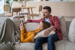 © DimaBerlin - Happy woman man relaxing on couch. Wife lying on husband lap using smartphone, smiling. Laughing man looks at phone screen. Spouses watching reels, shorts, short videos online at internet social media