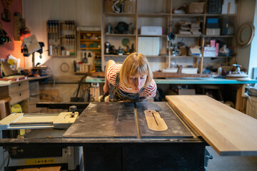 Woman handywoman cleans dust from table saw before using circular saw in workshop, preparing for accurate cuts. Ensuring clear workspace on factory, maintaining tools, safe and efficient woodwork