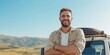 © Iryna - A man with a beard and a tan shirt is smiling and posing for a picture. He is standing next to a white vehicle with a tire rack. The scene has a relaxed and casual vibe, with the man looking happy