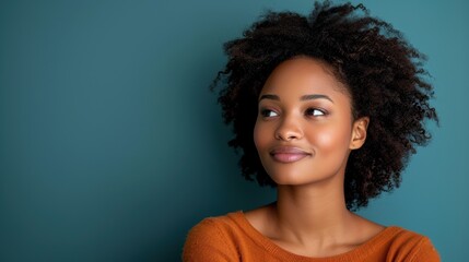 Wall Mural - Portrait of a Thoughtful Young Woman Looking to the Side Against a Teal Background, Wearing a Warm Orange Sweater and Displaying a Calm Expression, Emphasizing Natural Beauty and Confidence