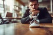 © Marat - A man at work sits tired and looks at an hourglass standing on the table