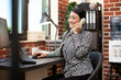 © DC Studio - Smiling asian professional uses landline phone to discuss project updates with colleague, seated at her desk in modern workspace. Businesswoman laughing on a call, having a friendly chat with client.