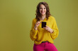 © Alliance - smiling fit woman using smartphone isolated on green
