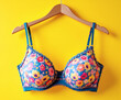 © linno - Closeup of a colorful bra on a hanger, front view, with a bright yellow background. Perfect for fashion, lingerie, and lifestyle themes.