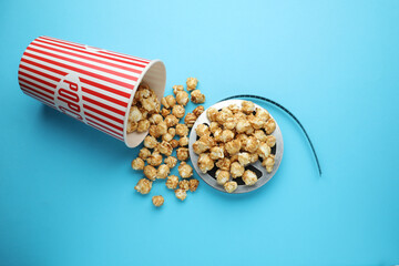 Wall Mural - Sweet popcorn and film reel on light blue background, top view. Watching movie