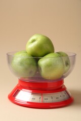 Wall Mural - Kitchen scale with apples on beige background, closeup