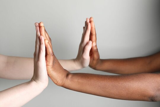 Wall Mural -  - stop racism. people of different skin colors joining hands on light grey background, closeup