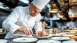 © Phirakhup - A professional chef meticulously plating a gourmet meal in a restaurant kitchen.