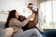 © Art_Photo - African family happy play at home, loving father holding and playing with baby while mother watches with joy, happy parenting moment full of love, affection, care and connection in cozy family at home
